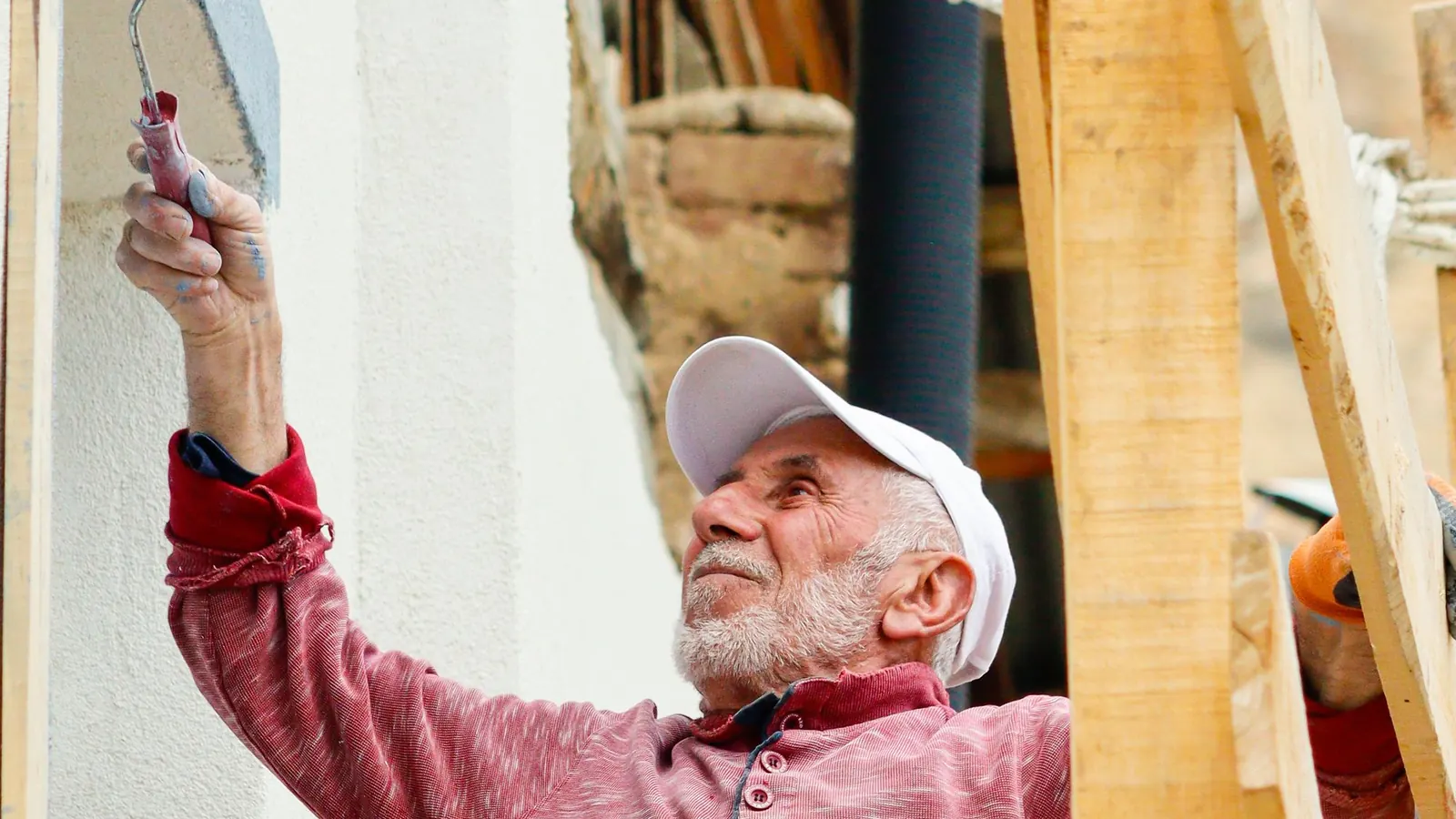 Decorator on a scaffold brushing masonry paint onto an exterior wall