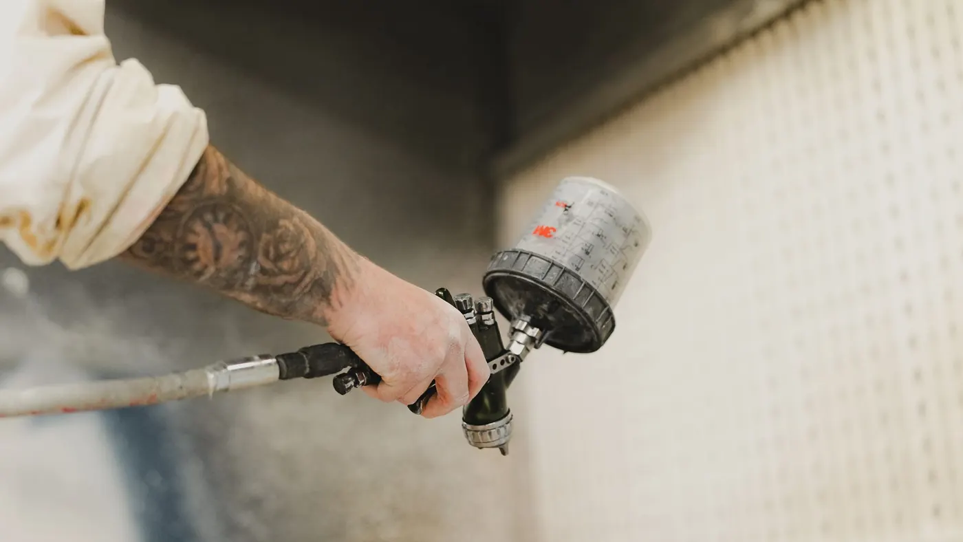 Close-up of a spray gun laying an even coat onto a flat panel