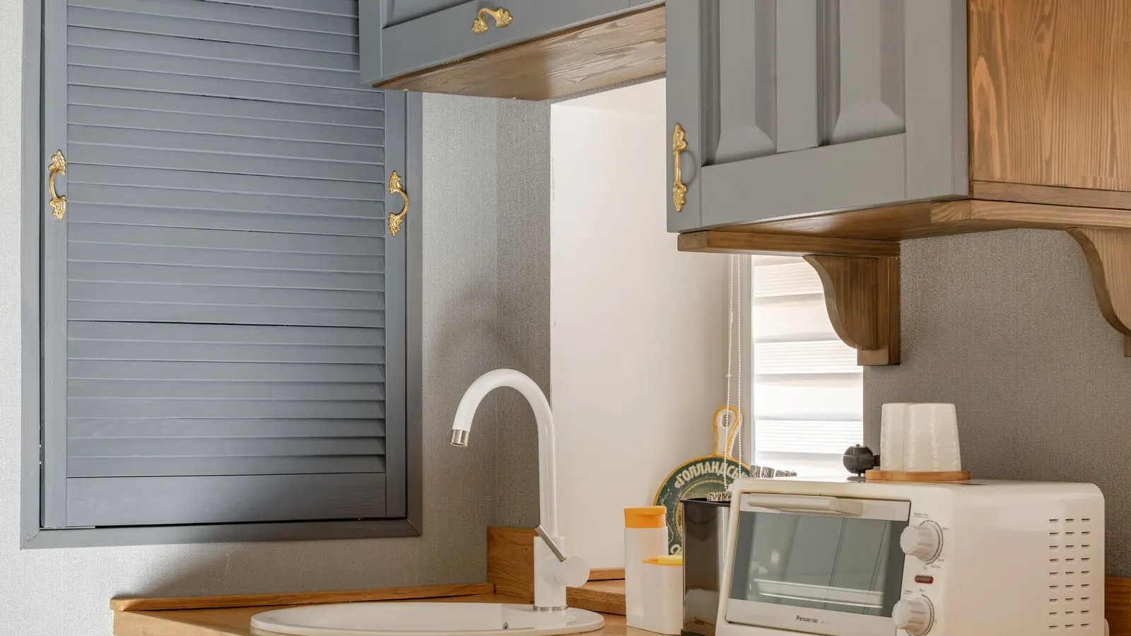 A kitchen with pale grey painted cabinet doors and wooden worktops