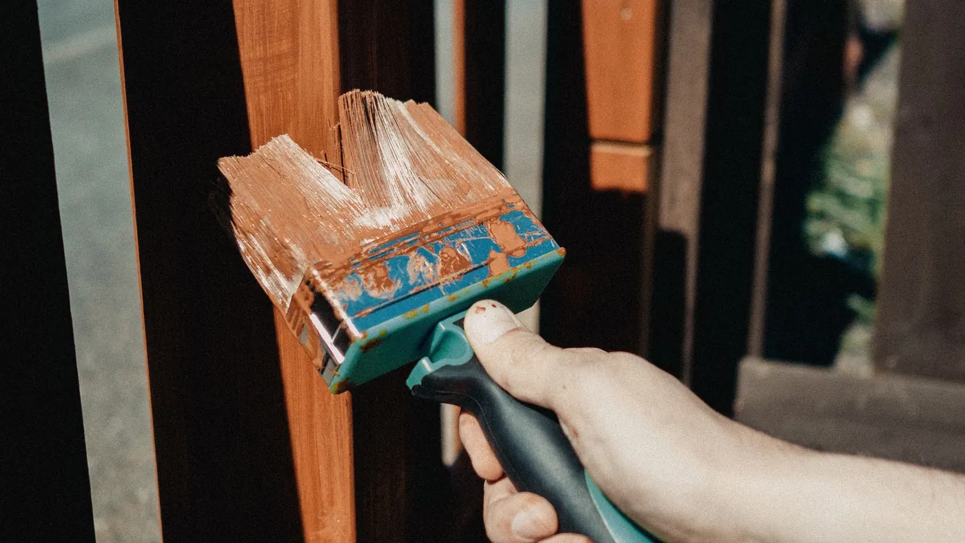 Brushing a dark preservative stain onto a garden fence