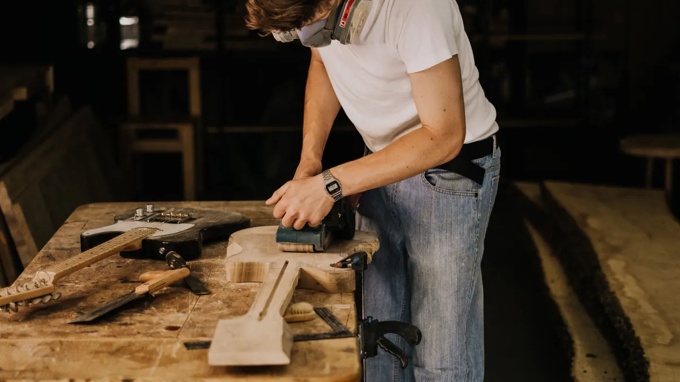 Sanding a length of timber to bare wood before staining