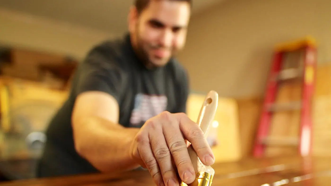 Brushing a dark varnish onto a wooden surface