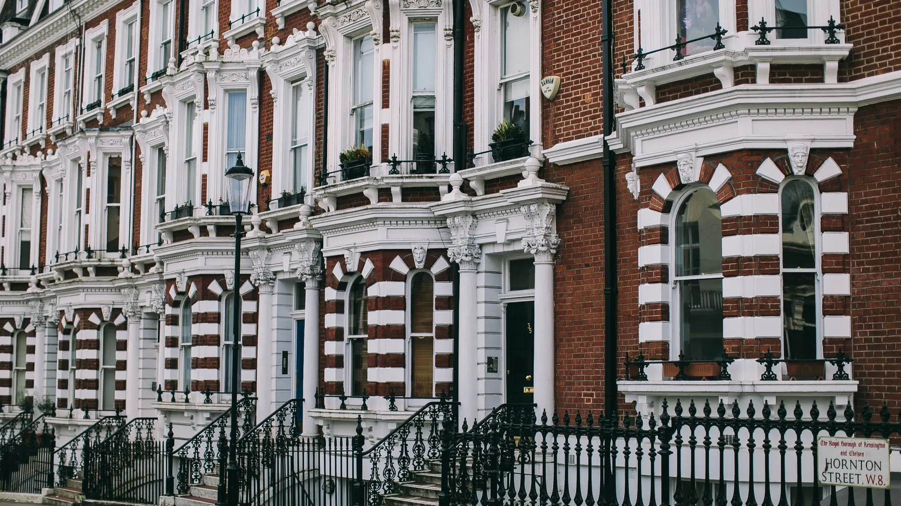 A row of red brick and white stucco Victorian houses on a London street