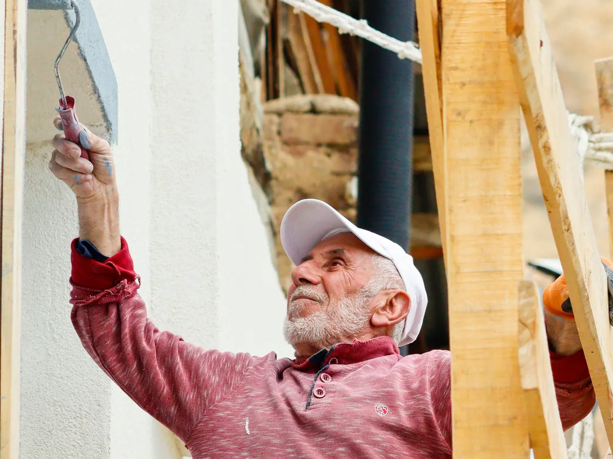 Painter on a scaffold platform brushing the exterior wall of a house