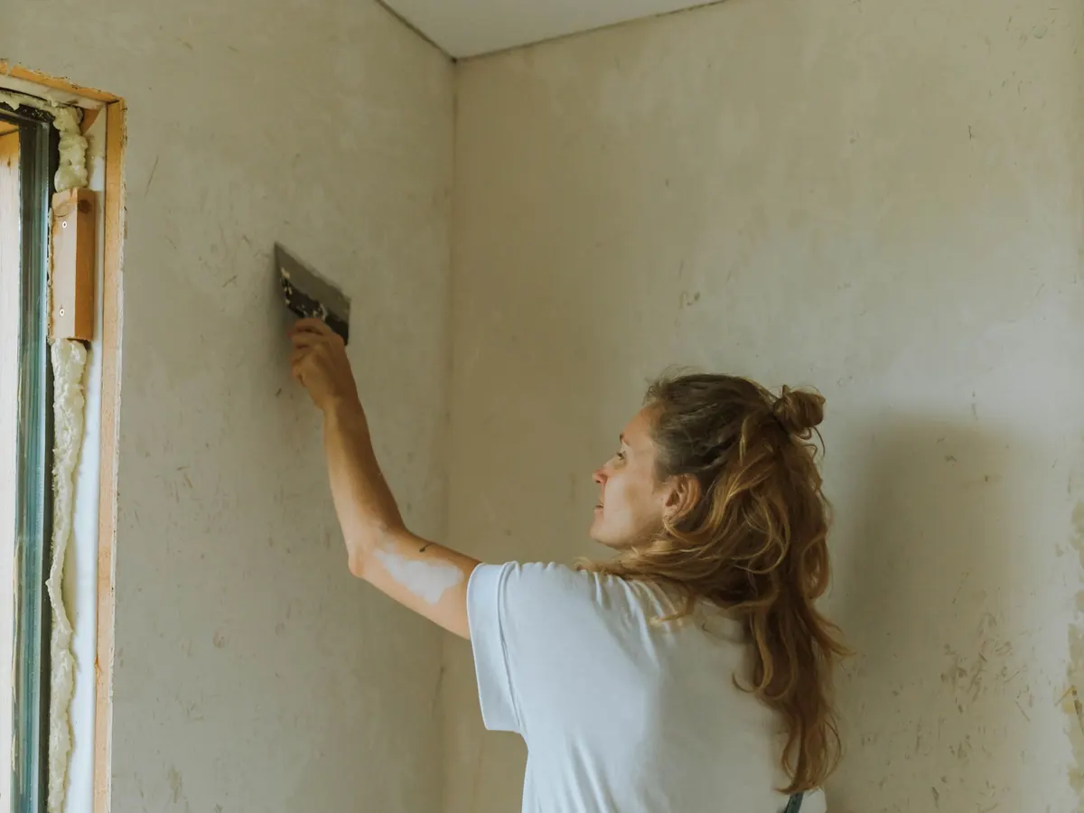 Decorator smoothing a drop of wallpaper down a wall from a stepladder