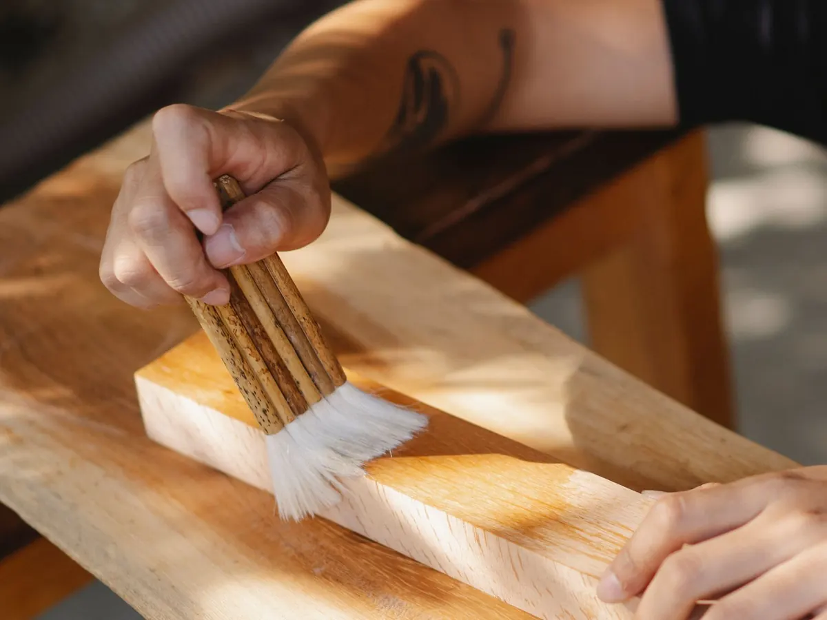 Brush drawing a warm stain along the grain of a plank