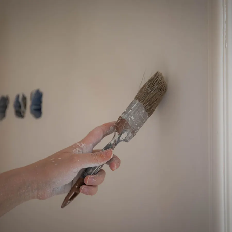 Brush testing colour patches on a bare plaster wall
