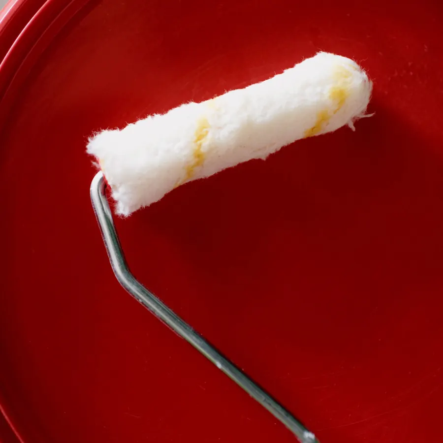 A clean roller resting on a red paint tin lid